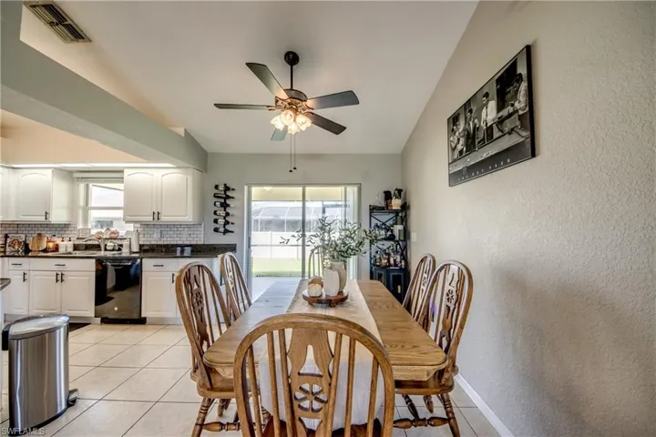 Dining room featuring a textured wall, light tile patterned floors, a ceiling fan, and lofted ceiling