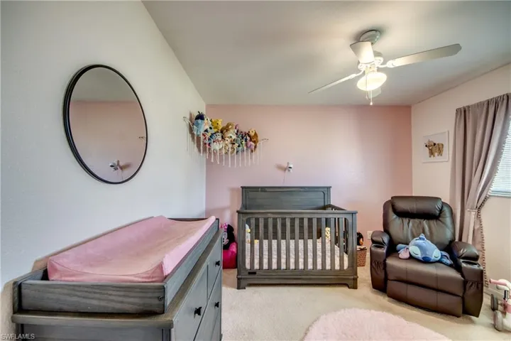 Bedroom featuring a crib, carpet, and a ceiling fan