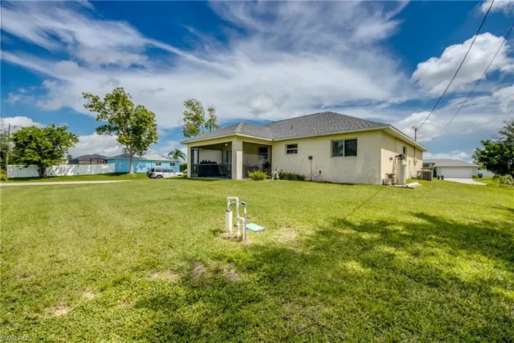 Back of house featuring a sunroom, stucco siding, a lawn, and roof with shingles