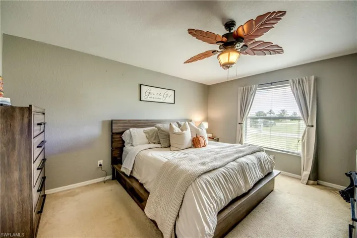 Bedroom with a textured wall, light carpet, ceiling fan, and a textured ceiling
