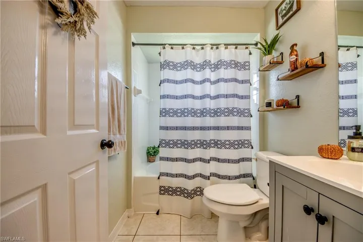 Full bath with shower / bathtub combination with curtain, vanity, light tile patterned flooring, and a textured wall