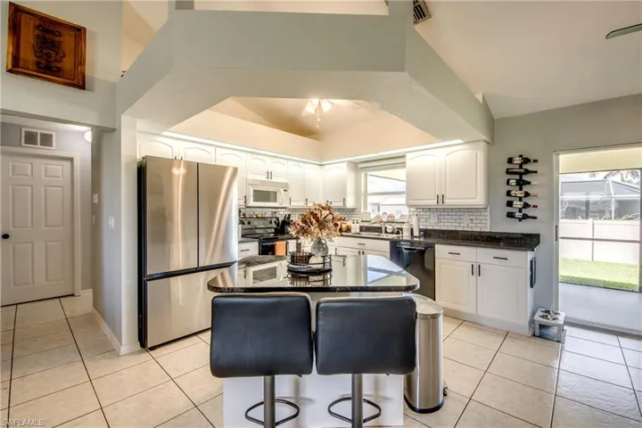 Kitchen featuring appliances with stainless steel finishes, light tile patterned floors, a kitchen breakfast bar, white cabinetry, and a center island
