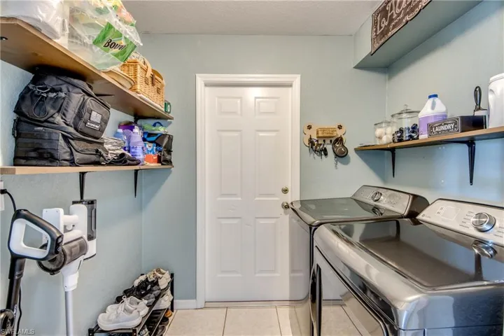 Laundry area featuring light tile patterned flooring, separate washer and dryer, and a textured ceiling