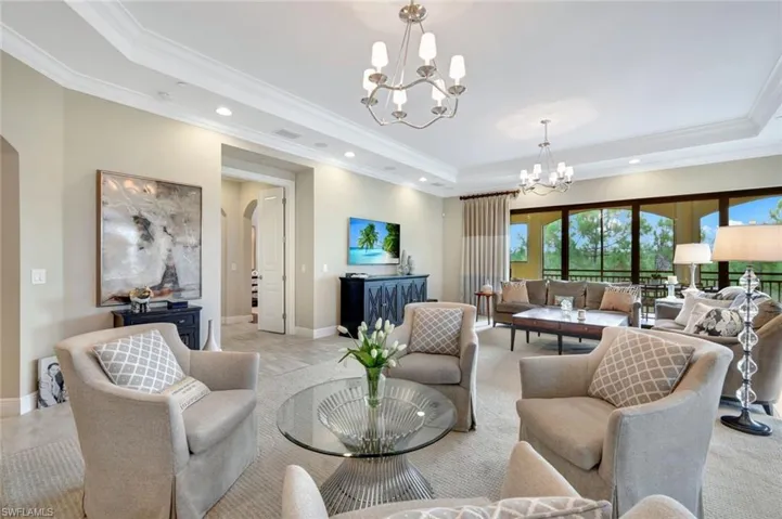Living room with ornamental molding, an inviting chandelier, and a raised ceiling