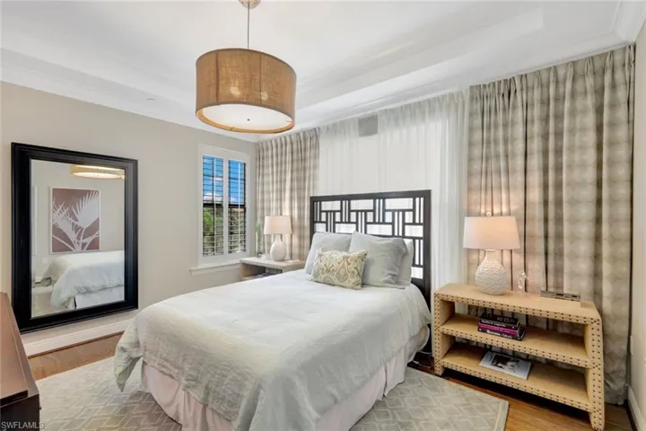 Bedroom with hardwood / wood-style flooring, crown molding, and a tray ceiling