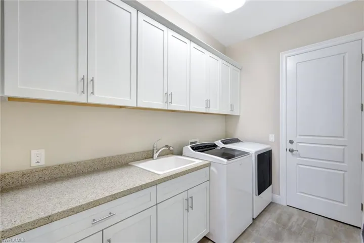 Laundry area featuring washer and clothes dryer, sink, cabinets, and light tile patterned floors