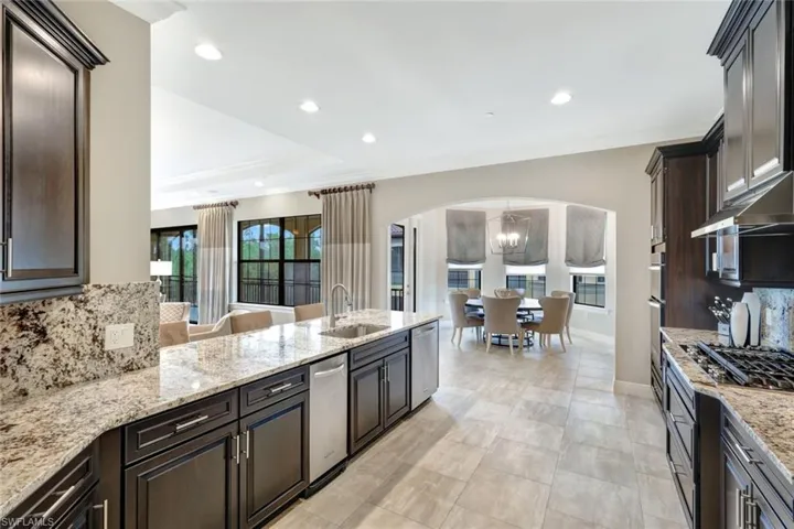 Kitchen with decorative backsplash, light granite countertops, dark brown cabinetry, and sink