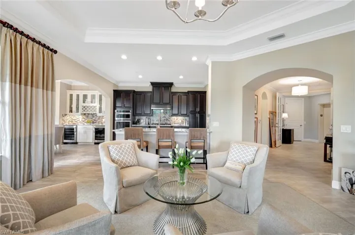 Living room with crown molding, a chandelier, light tile patterned floors, wine cooler, and a tray ceiling