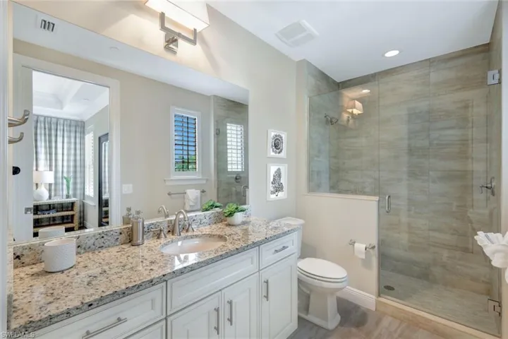 Bathroom with walk in shower, vanity, crown molding, and toilet