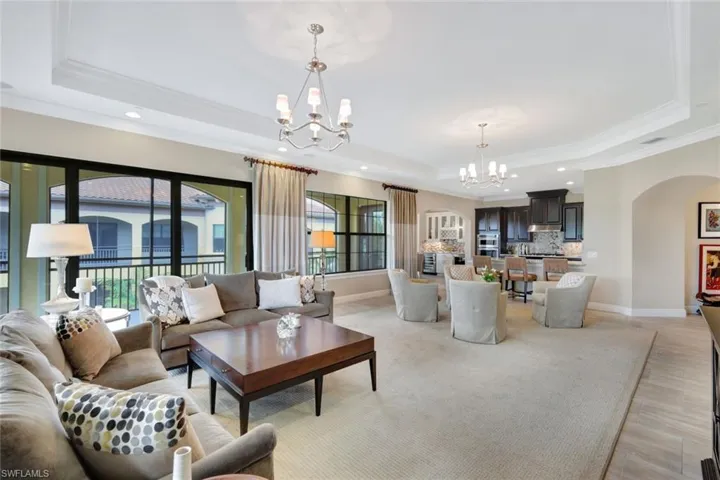 Living room with crown molding, a raised ceiling, and a chandelier