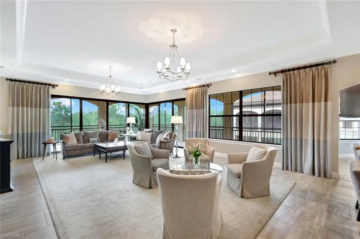 Living room featuring plenty of natural light, a chandelier, and a tray ceiling