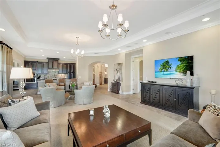 Living room featuring a raised ceiling, crown molding, and a notable chandelier
