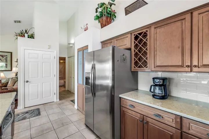 Kitchen featuring a high ceiling, stainless steel appliances, light stone counters, and light tile patterned flooring