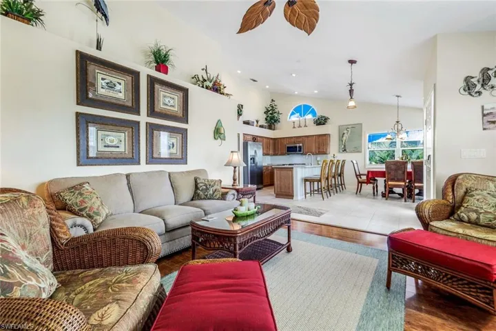 Living room with sink, light hardwood / wood-style floors, vaulted ceiling, and an inviting chandelier