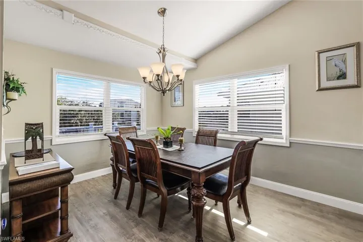 Dining area featuring hardwood / wood-style floors, an inviting chandelier, a wealth of natural light, and vaulted ceiling