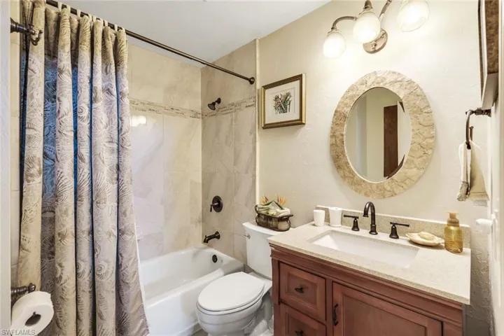 Full bathroom featuring shower / bath combination with curtain, vanity, and toilet