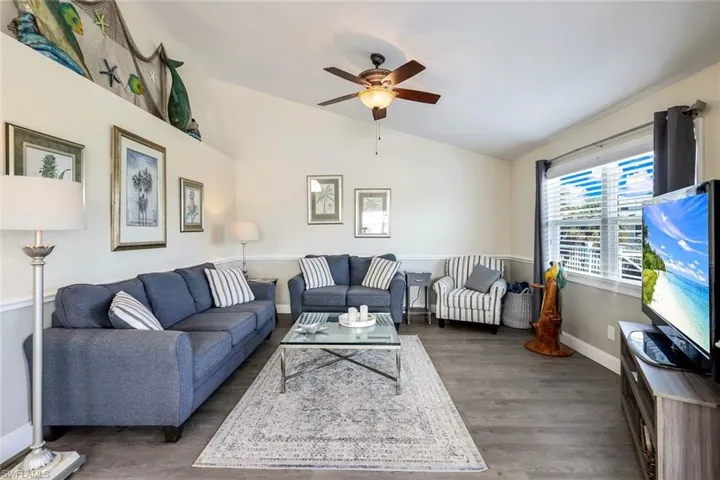 Living room featuring ceiling fan, dark hardwood / wood-style floors, and vaulted ceiling