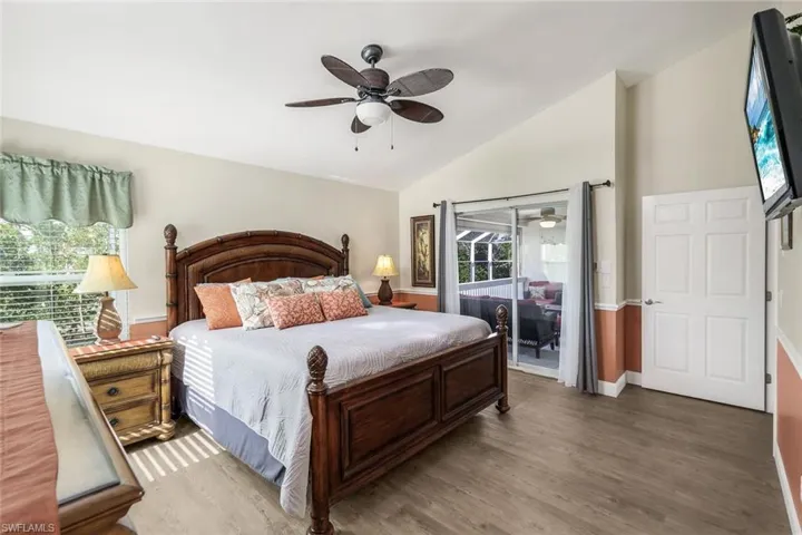 Bedroom with access to exterior, dark hardwood / wood-style floors, ceiling fan, and lofted ceiling