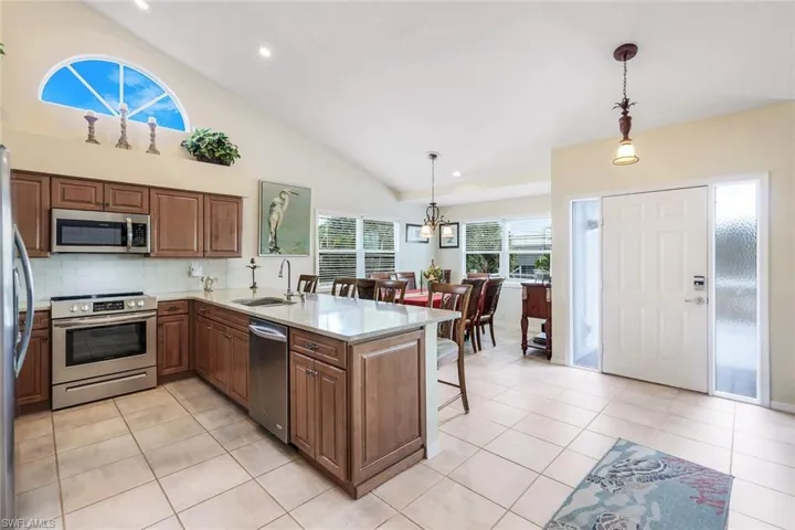 Kitchen featuring kitchen peninsula, appliances with stainless steel finishes, decorative light fixtures, and sink