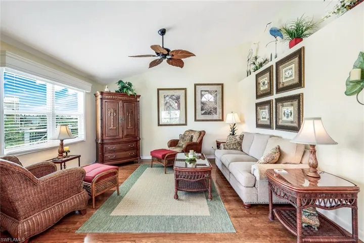 Living room with ceiling fan, dark wood-type flooring, and vaulted ceiling