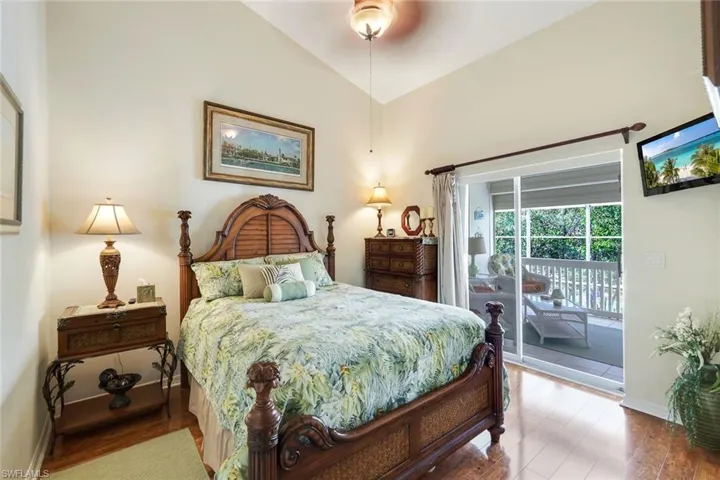 Bedroom with access to exterior, ceiling fan, wood-type flooring, and vaulted ceiling