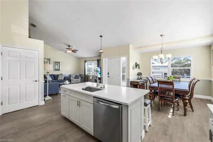 Kitchen with a kitchen island with sink, a healthy amount of sunlight, hanging light fixtures, and stainless steel dishwasher