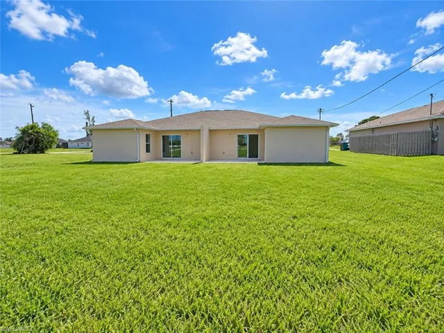 Expansive grassy yard with a stucco exterior and multiple sliding glass doors