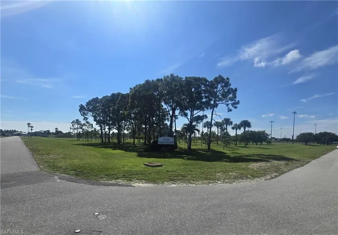 Expansive paved roadways leading to a landscaped entrance with a variety of mature trees and established green space