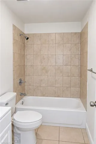 Built-in bathtub with shower, tiled surround, and chrome fixtures