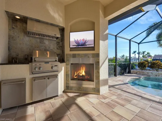 View of patio / terrace with grilling area, a lanai, a fireplace, and exterior kitchen