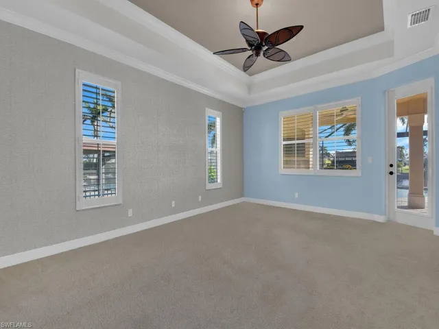 Ground floor Master Bedroom featuring carpet floors, ornamental molding, and a raised ceiling