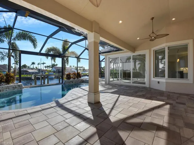 View of swimming pool with ceiling fan, a patio, glass enclosure, and a water view