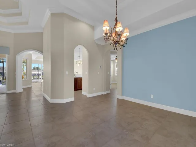 Dining room with a towering ceiling, a chandelier, tile patterned flooring, a tray ceiling, and crown molding