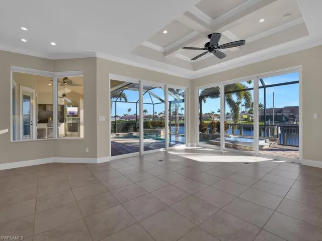 Tiled spare room featuring crown molding, ceiling fan, beam ceiling, a water view, and coffered ceiling