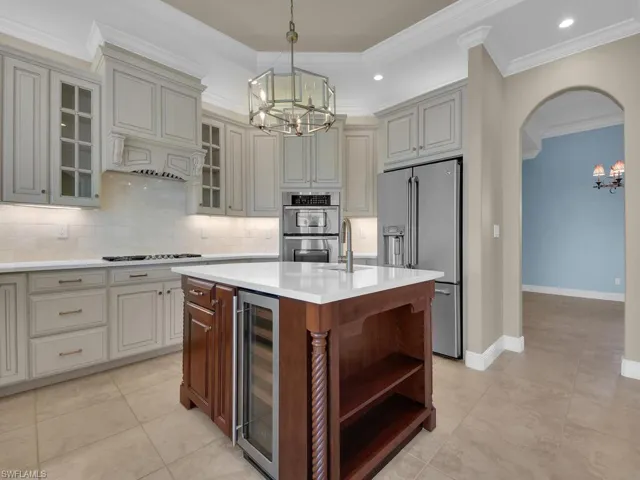 Kitchen featuring a notable chandelier, an island with sink, appliances with stainless steel finishes, and wine cooler