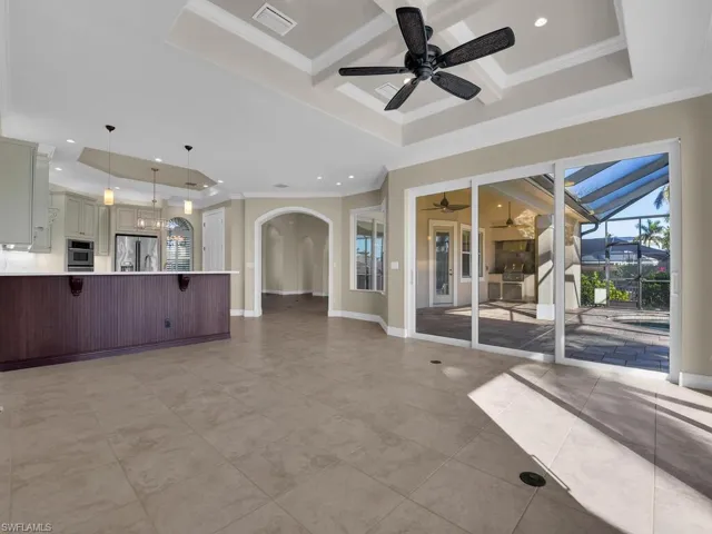 Family Room with ornamental molding, coffered ceiling, light tile patterned floors, ceiling fan, and a raised ceiling