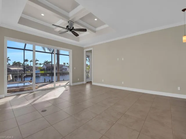 Unfurnished room featuring coffered ceiling, light tile patterned floors, crown molding, and a water view