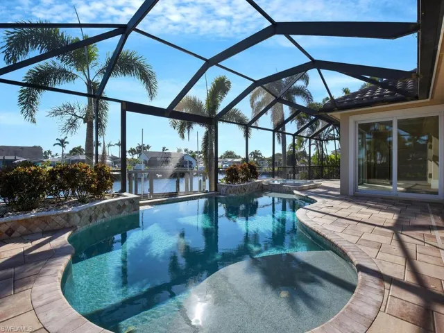 View of swimming pool featuring a water view, a patio, an in ground hot tub, and glass enclosure