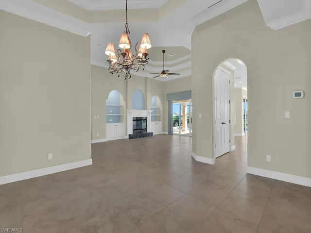Dining room with a towering ceiling, a chandelier, tile patterned flooring, a tray ceiling, and crown molding