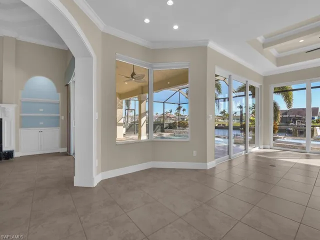 Empty room featuring crown molding, a water view, a high end fireplace, and ceiling fan