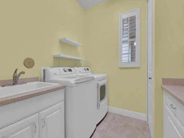 Clothes washing area featuring separate washer and dryer, sink, and cabinets