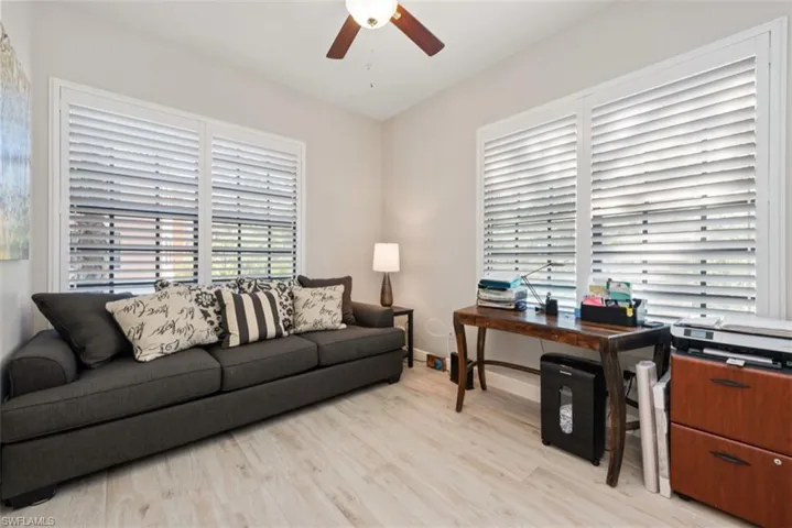 Living room with light wood-type flooring, an office area, and ceiling fan