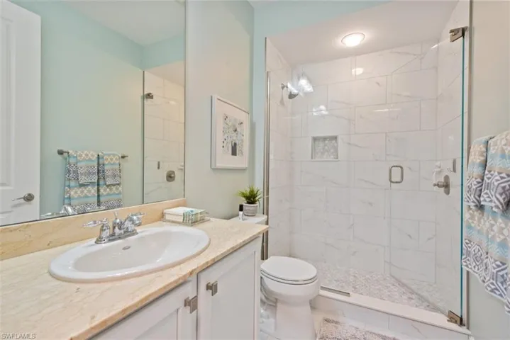 Bathroom featuring a marble finish shower and vanity