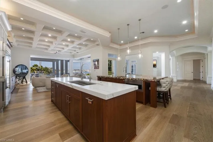 Kitchen with open floor plan, recessed lighting, coffered ceiling, hanging light fixtures, and arched walkways