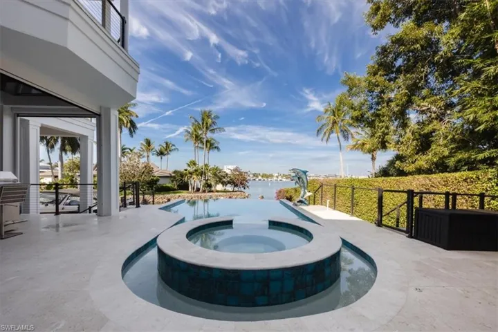 View of swimming pool featuring a patio area, a pool with connected hot tub, and a water view
