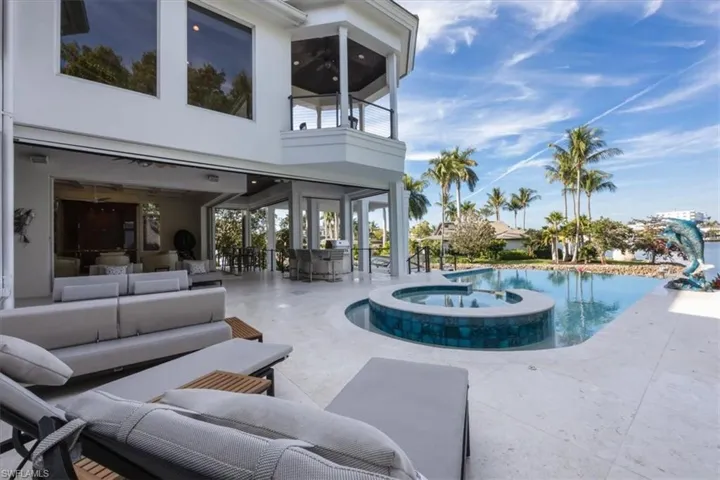 View of swimming pool featuring a balcony, a sunroom, a pool with connected hot tub, an outdoor living space, and a patio