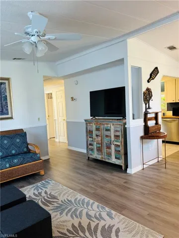 Living room featuring light wood-style floors, crown molding, and ceiling fan