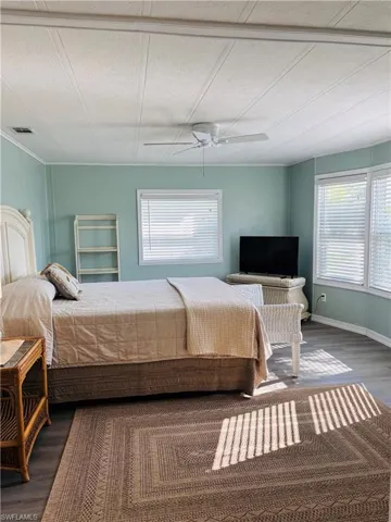 Bedroom featuring wood finished floors, multiple windows, and ceiling fan