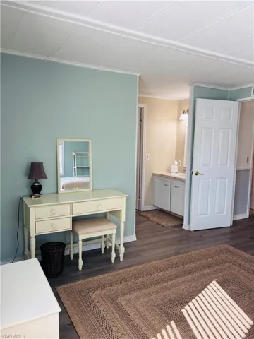 Home office with dark wood finished floors and ornamental molding