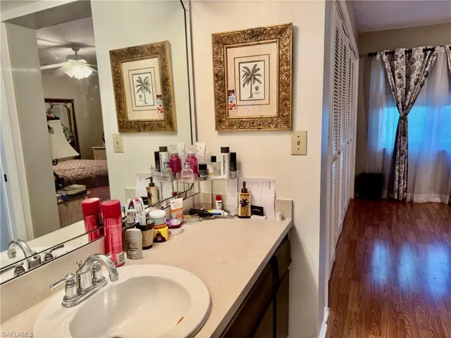 Ensuite bathroom featuring vanity, dark wood-type flooring, and a ceiling fan
